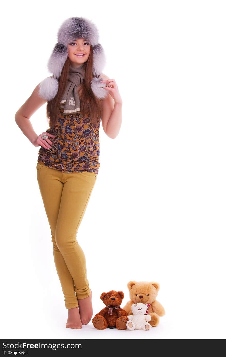 Beautiful brunette in a fur hat standing next to a few teddy bears