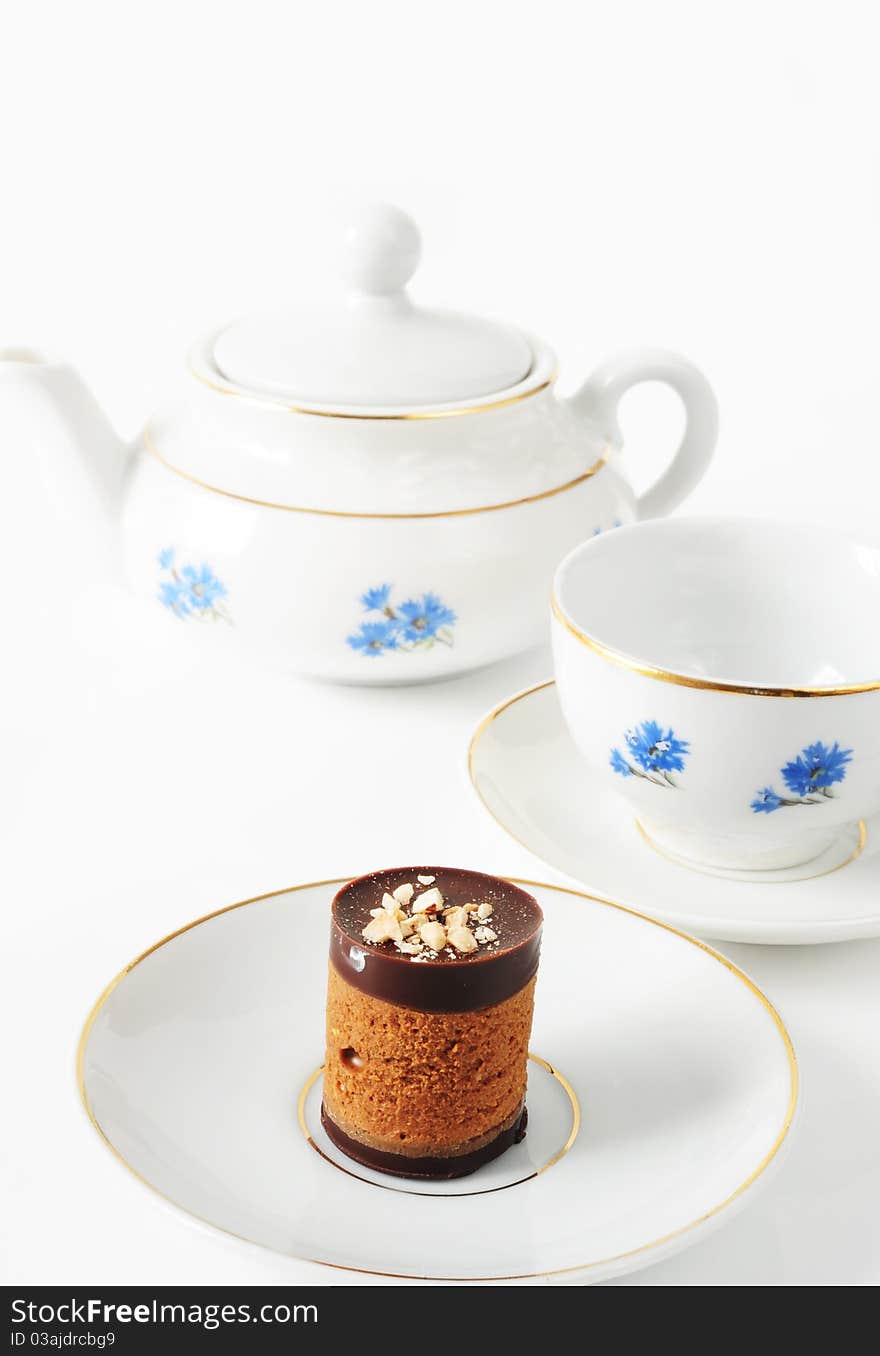 Teapot and cup with cornflowers and cake on a white background. Teapot and cup with cornflowers and cake on a white background