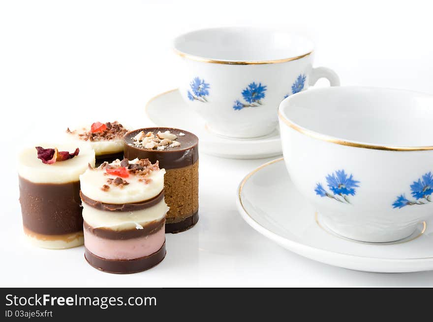 Two cups with cornflowers and four cakes on a white background. Two cups with cornflowers and four cakes on a white background