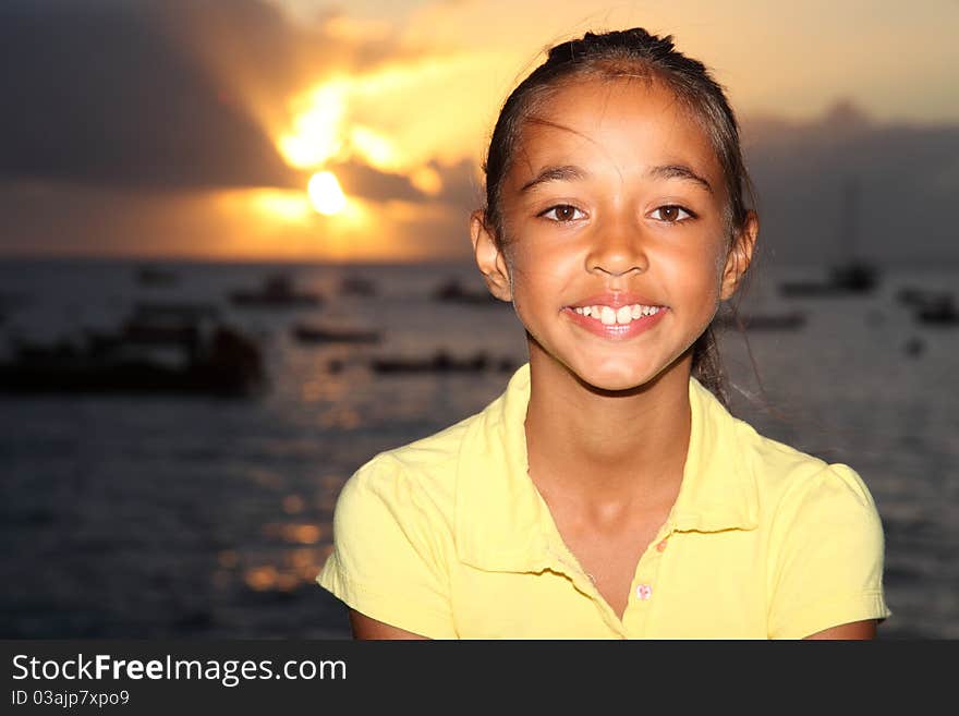 Happy mixed race school girl by seaside at sunset