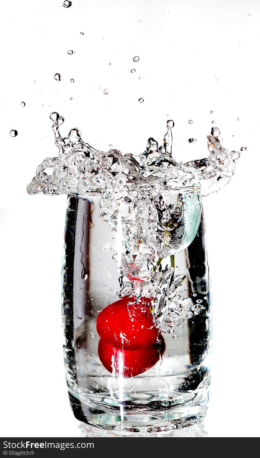 Two red cherrys splashing into a glass