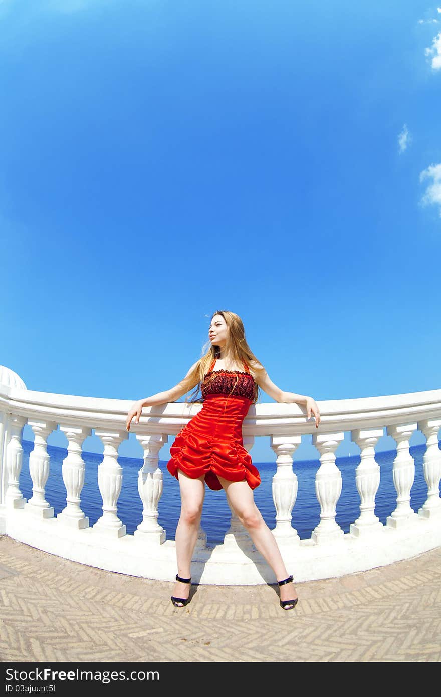 The image of a beautiful girl in the red dress on the beach