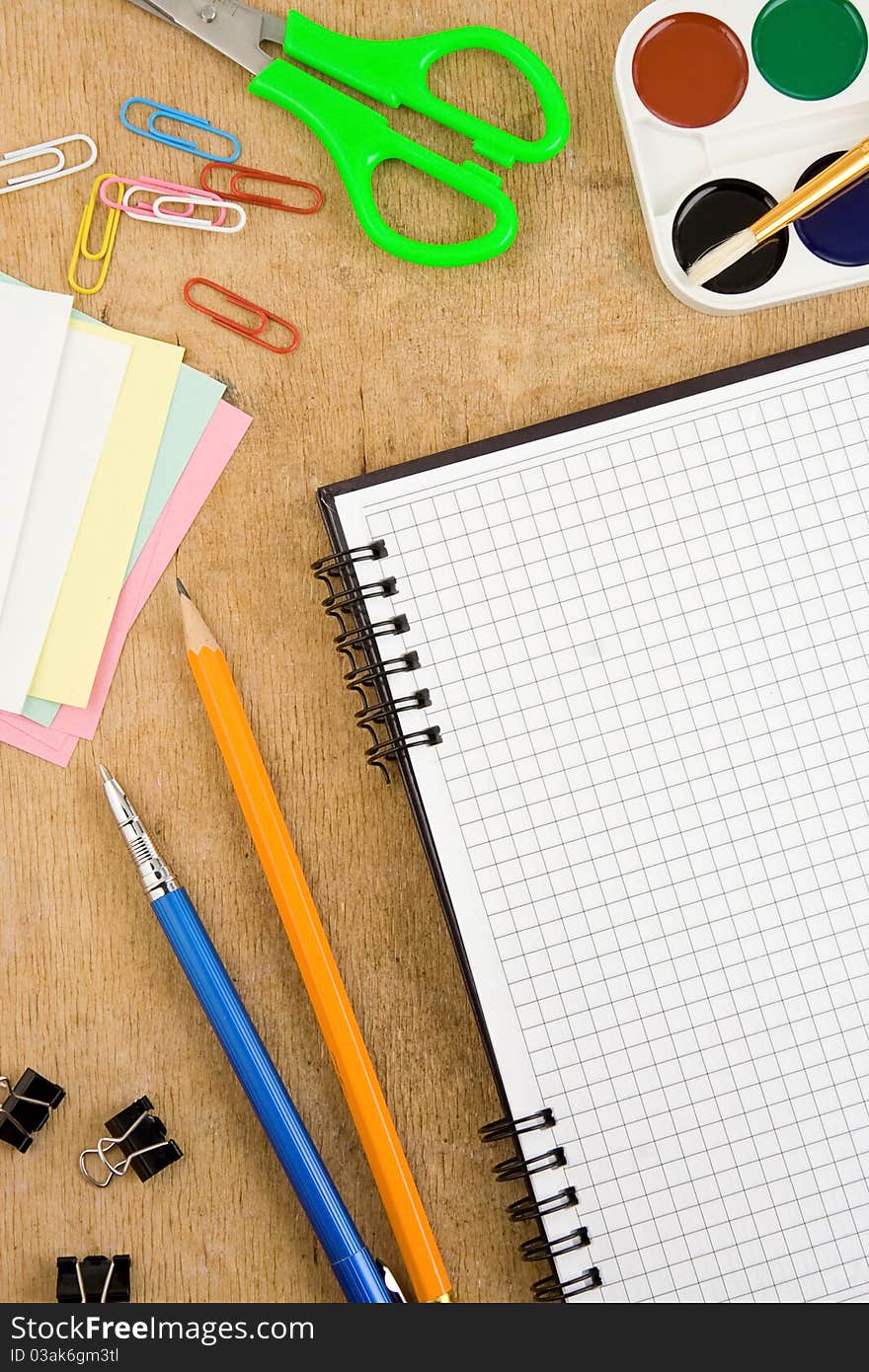 School accessories and checked notebook on wooden table