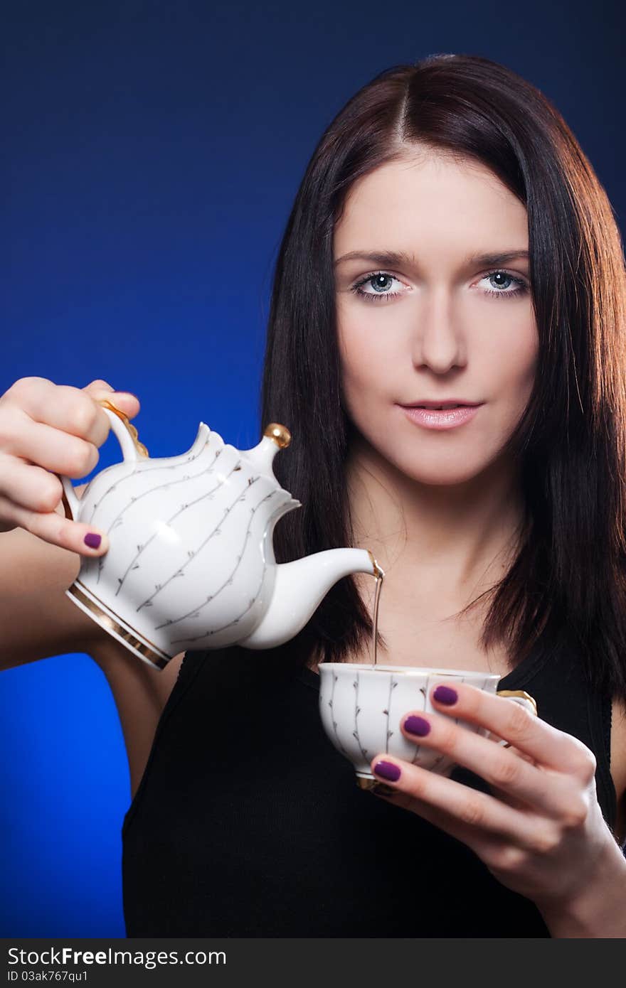 Beautiful girl pouring tea from a teapot into a cup. Beautiful girl pouring tea from a teapot into a cup