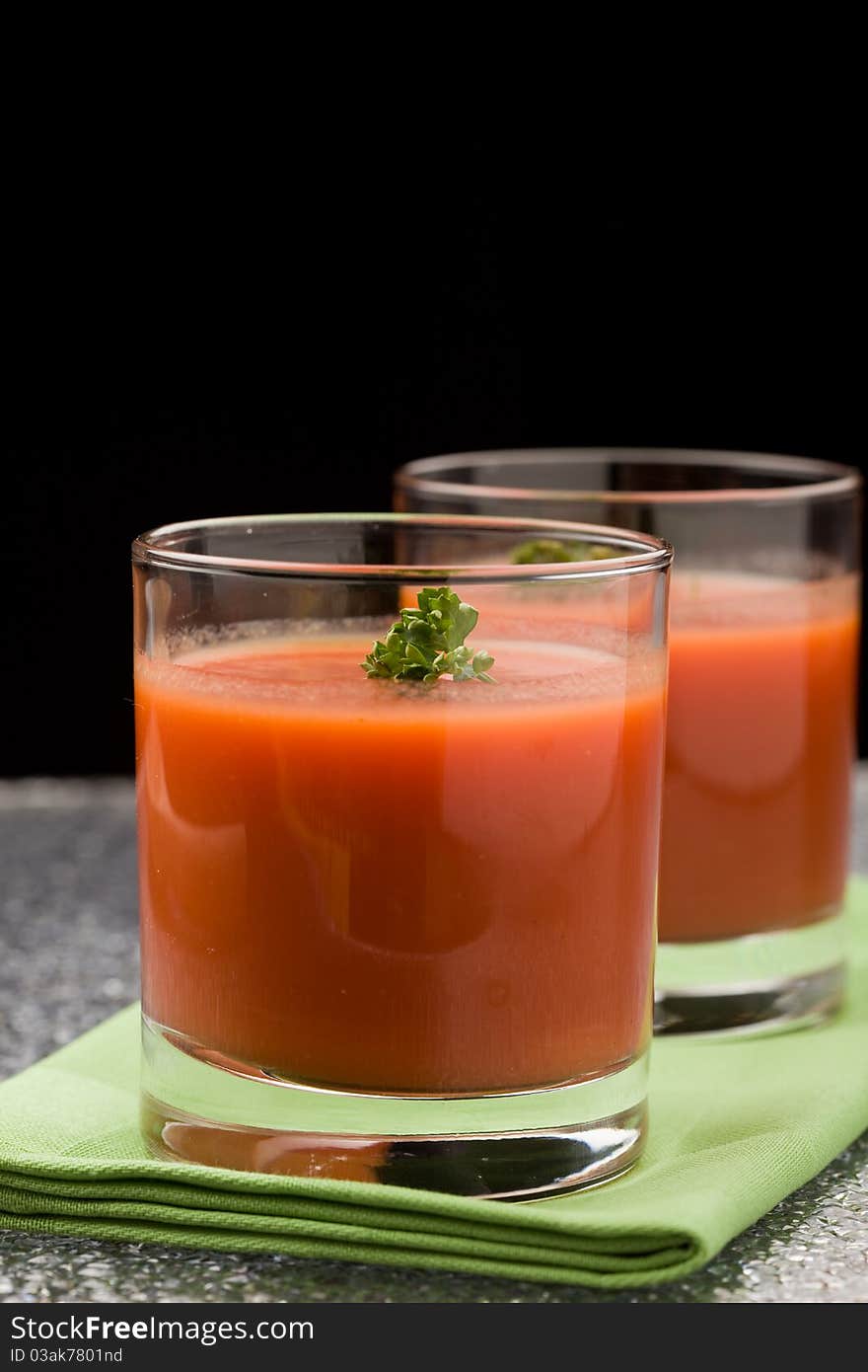 Photo of delicious tomatoe juice with parsley in glass on green cloth