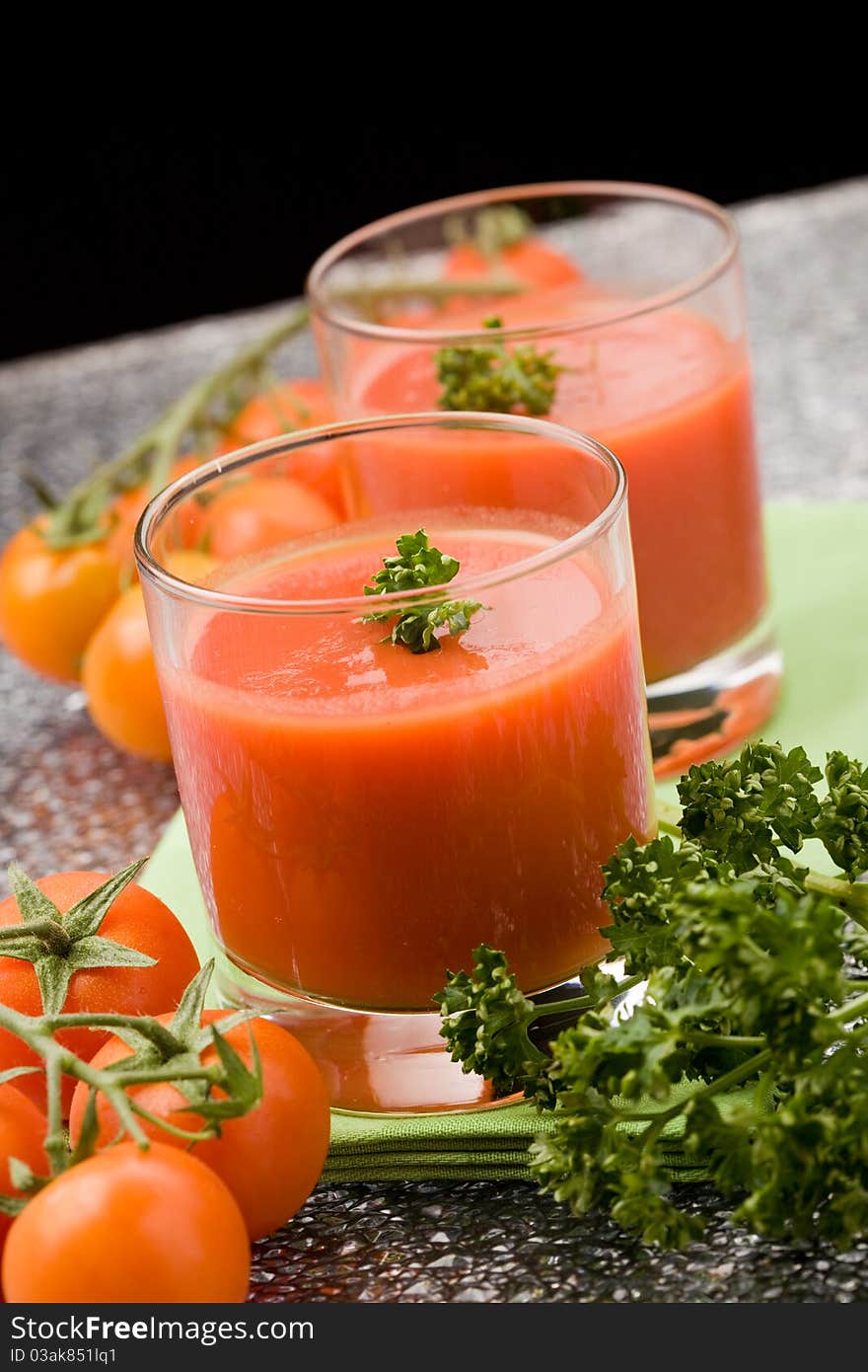 Photo of delicious tomatoe juice with parsley in glass on green cloth