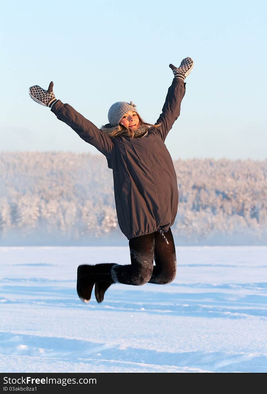 Girl jumps in the snow in the sun