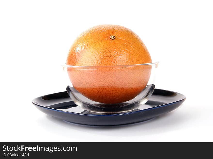 Grapefruit in a glass vase on a dark blue plate, white background