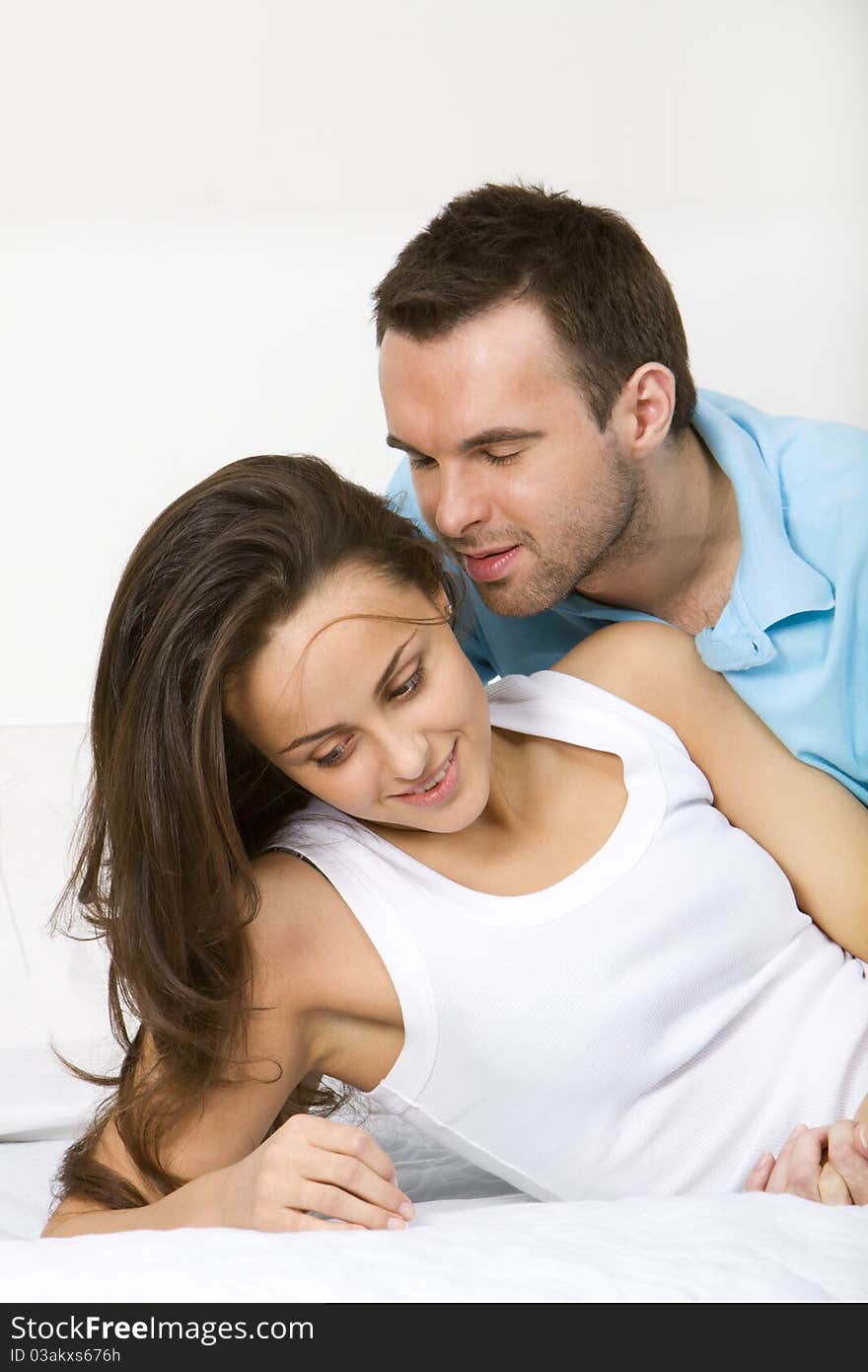 Young couple lying on a white sofa embracing. Young couple lying on a white sofa embracing