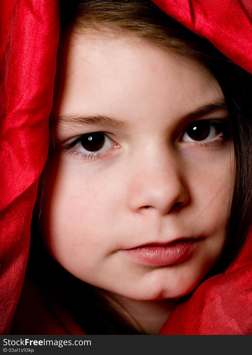 A picture of a young girl playing fashion model in a red scarf. A picture of a young girl playing fashion model in a red scarf