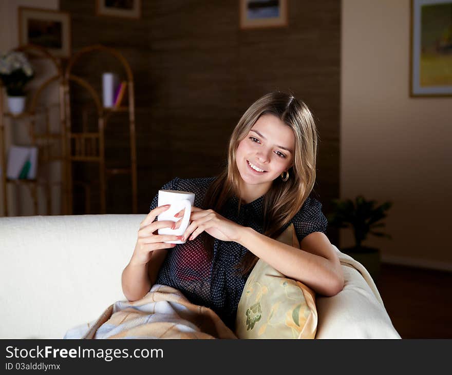 A young girl sitting on the sofa with a mug. A young girl sitting on the sofa with a mug