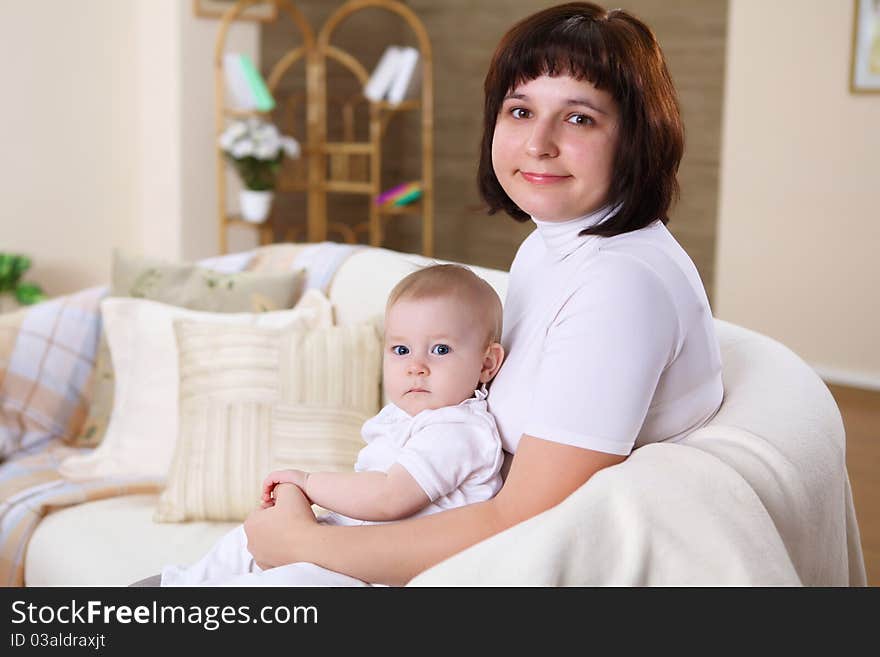 A young mother playing with her infant baby at home. A young mother playing with her infant baby at home