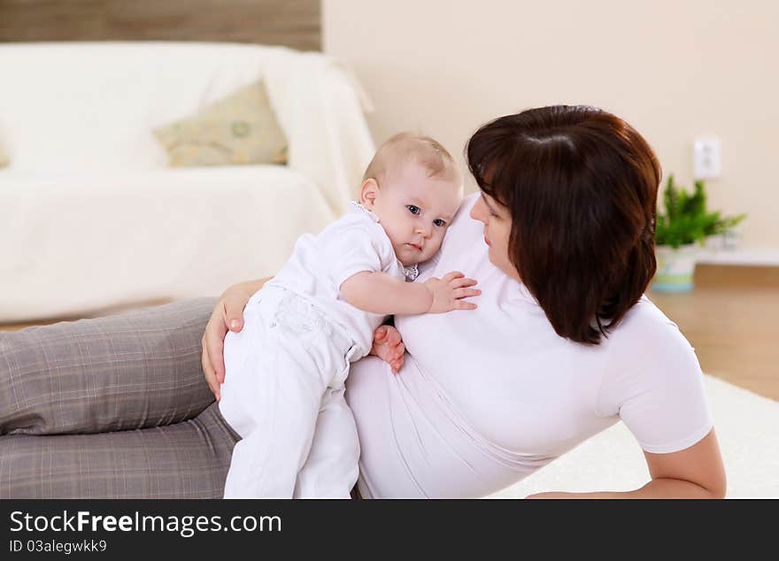 A young mother playing with her infant baby at home. A young mother playing with her infant baby at home