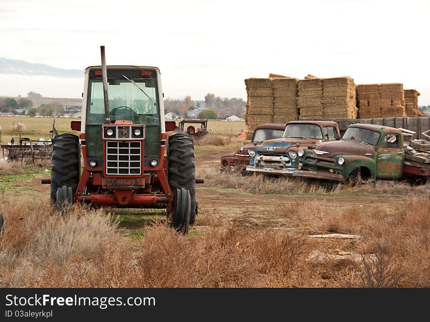 Several antique trucks and an old broken down tractor on a rural farm in Idaho. Several antique trucks and an old broken down tractor on a rural farm in Idaho