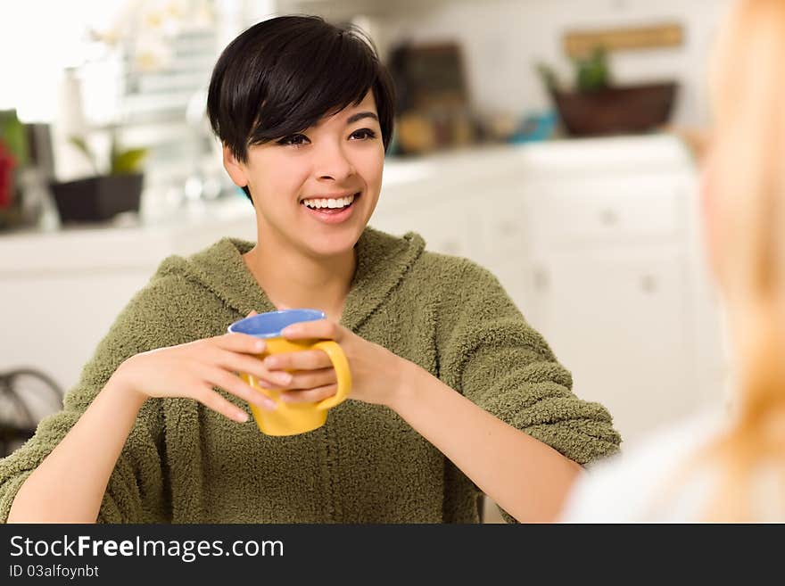 Multi-ethnic Young Attractive Woman Socializing with Friend in Her Kitchen. Multi-ethnic Young Attractive Woman Socializing with Friend in Her Kitchen.