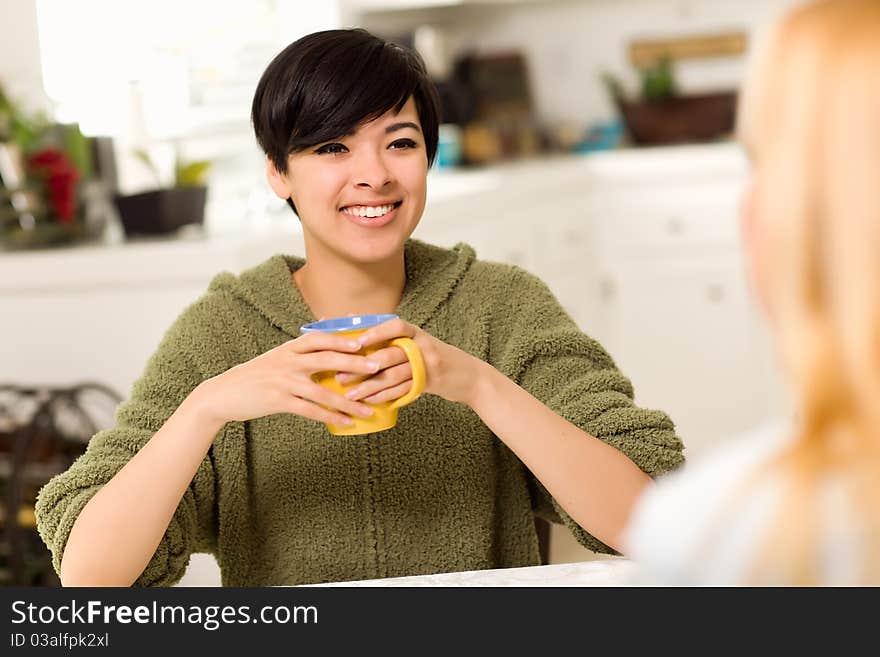 Multi-ethnic Young Attractive Woman Socializing with Friend in Her Kitchen. Multi-ethnic Young Attractive Woman Socializing with Friend in Her Kitchen.