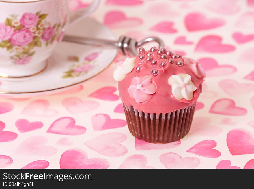 Cup cake and tea cup on pink background with hearts