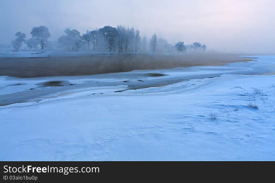 Calm winter landscape of a lake and trees during sunrises,jilin,china.