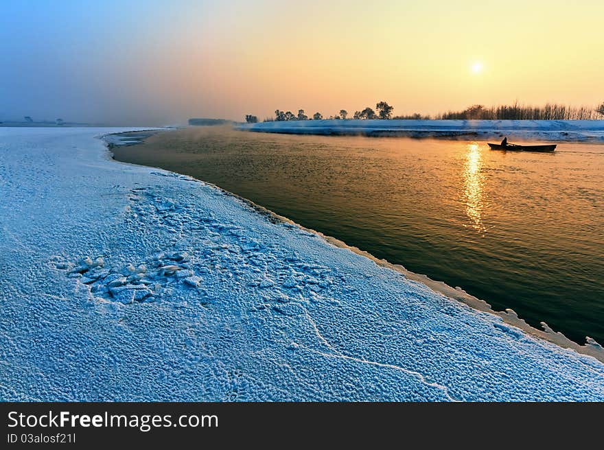 Calm winter landscape of a lake and trees during sunset.