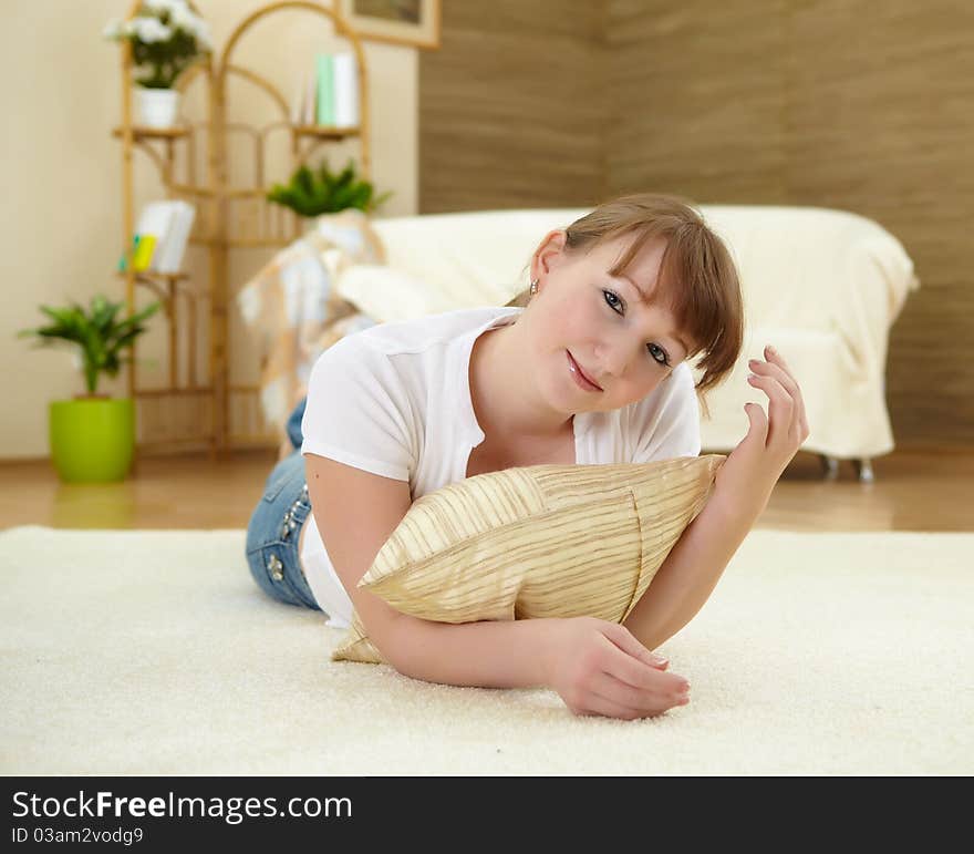 A young girl with at home relaxing on the carpet in her living room. A young girl with at home relaxing on the carpet in her living room