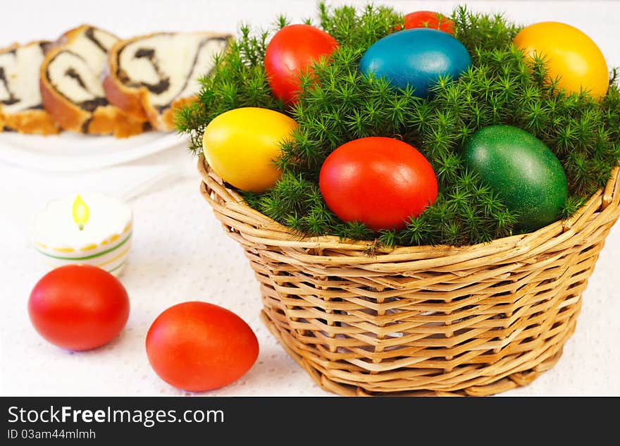 Easter basket with painted eggs and sponge cake in background