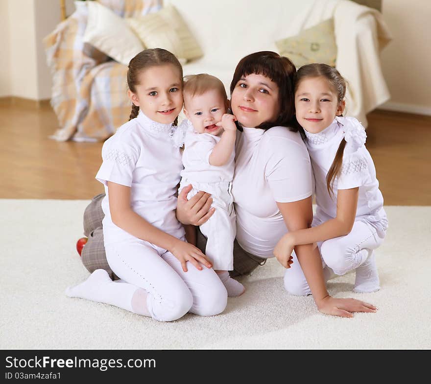 Mother with her three daughters at home on the carpet in the living room. Mother with her three daughters at home on the carpet in the living room