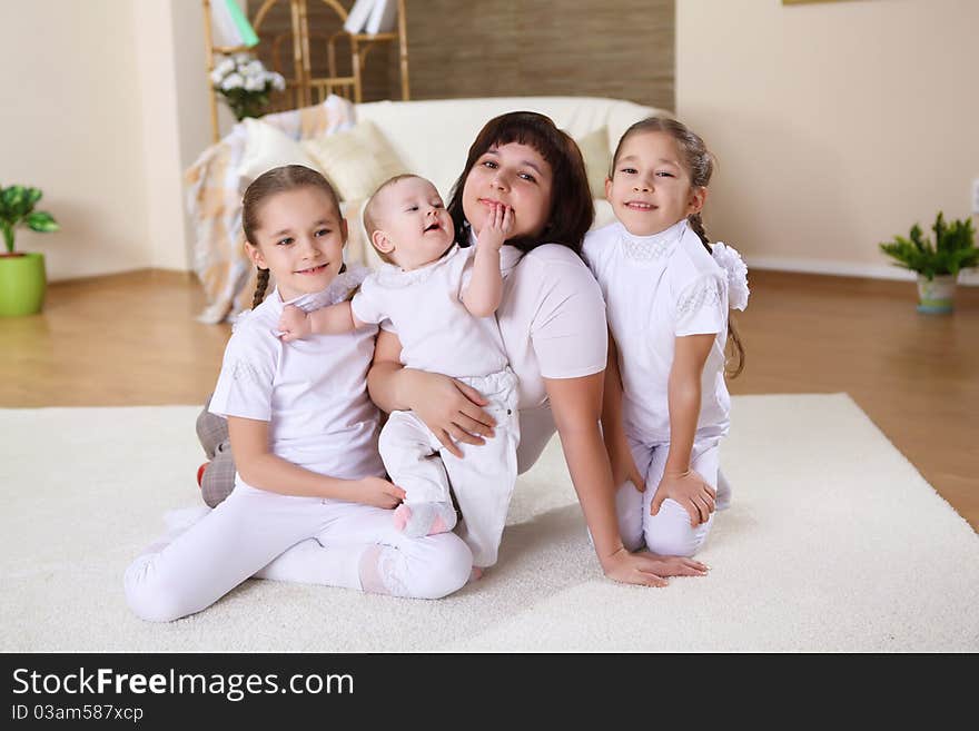 Mother with her three daughters at home on the carpet in the living room. Mother with her three daughters at home on the carpet in the living room