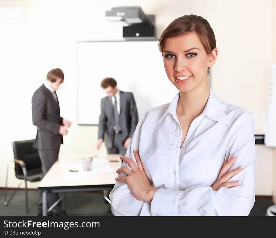 Young and attractive businesswoman in an office with collegues on the background. Young and attractive businesswoman in an office with collegues on the background