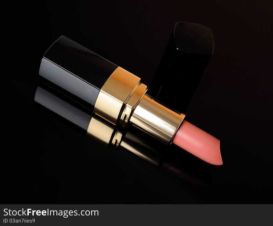 Luxury pink lipstick on black background. make-up accessories