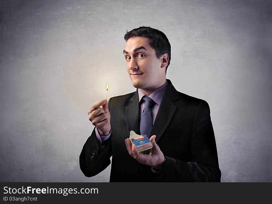 Businessman holding a safety match. Businessman holding a safety match