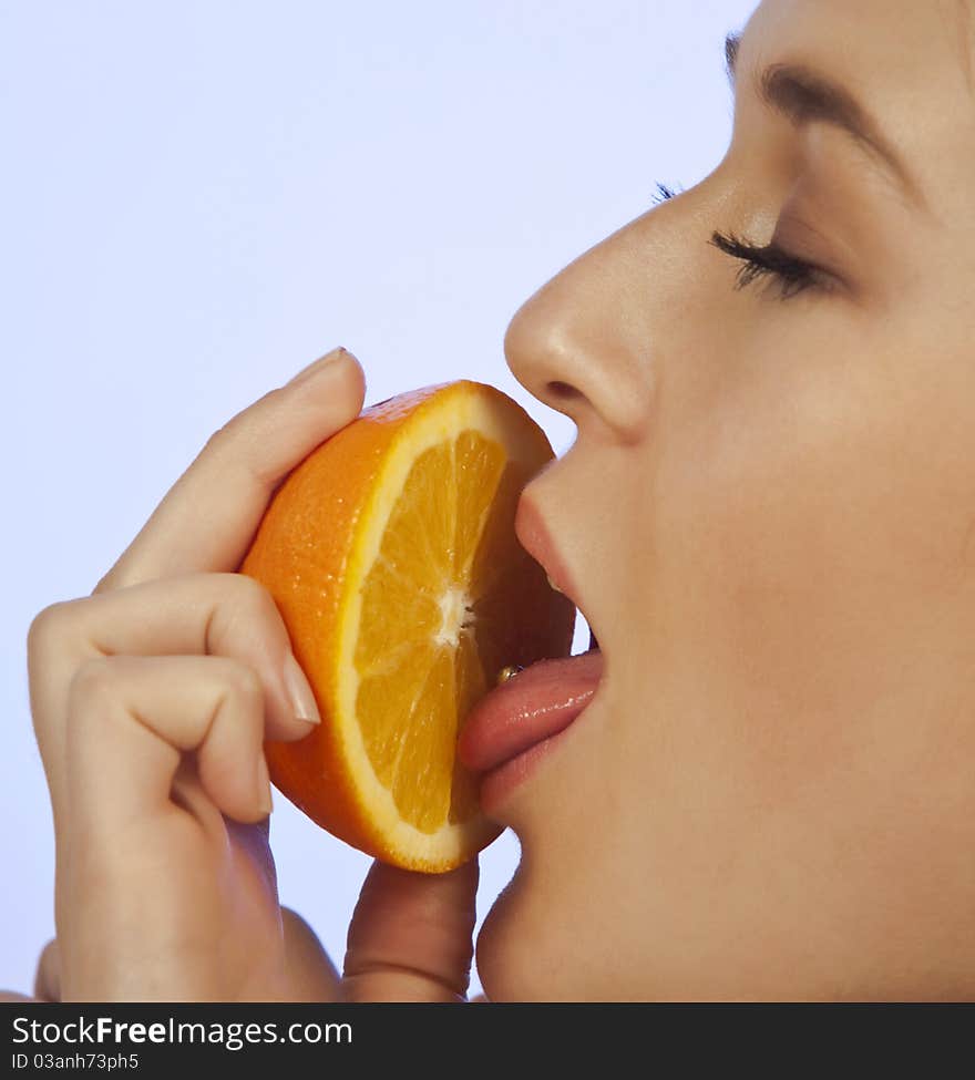 Young woman enjoying a slice of orange