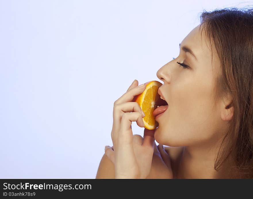 Young woman enjoying a slice of orange