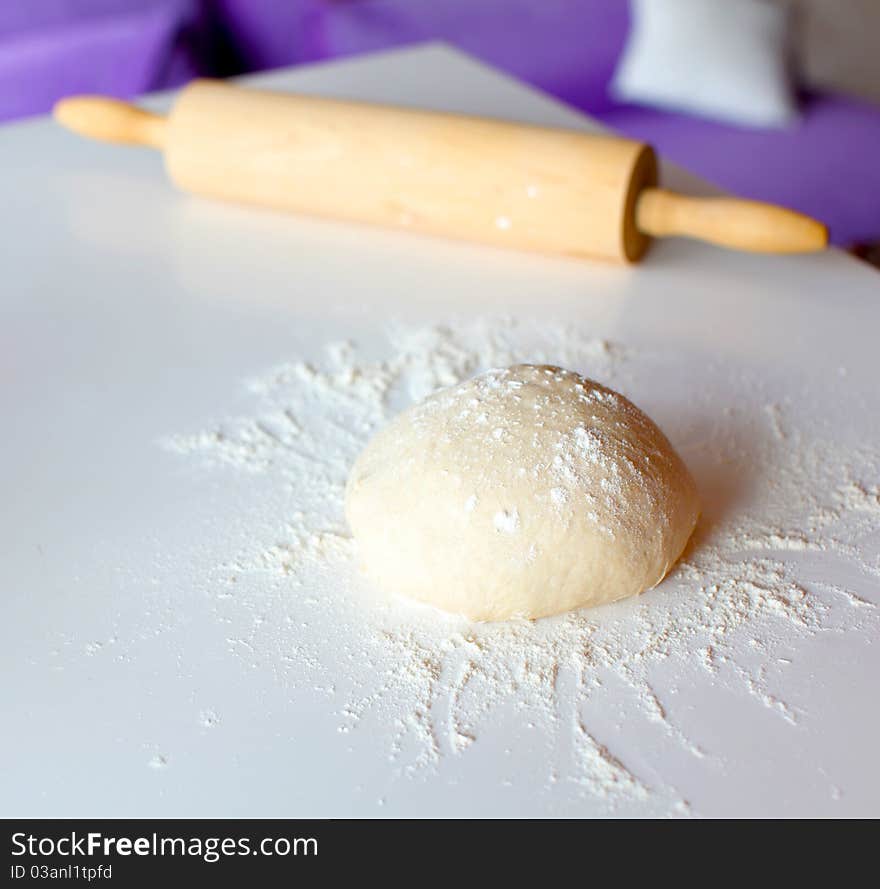 Risen dough from wheat flour for bread making on the kitchen top with the rolling pin. Risen dough from wheat flour for bread making on the kitchen top with the rolling pin.