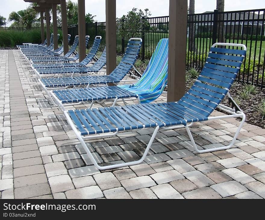 A row of blue pool lounge chairs. A row of blue pool lounge chairs.