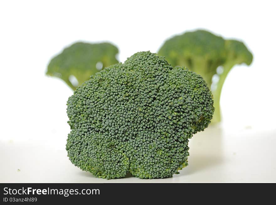 Broccoli vegetable standing on a white shiny table isolated on white background.