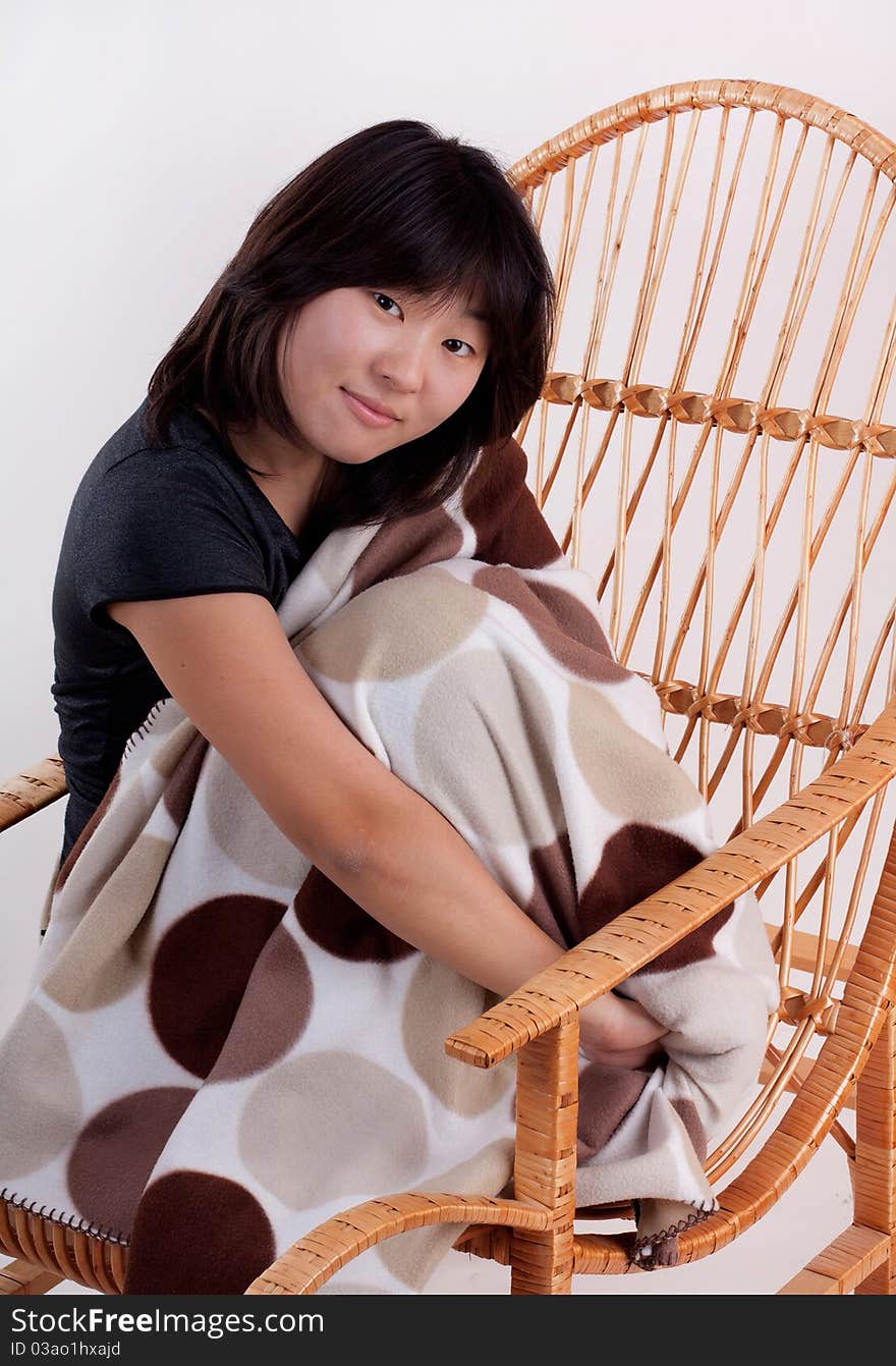 Attractive cheerful  young Asian woman sitting in the rocking-chair. Attractive cheerful  young Asian woman sitting in the rocking-chair