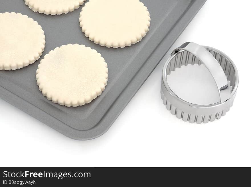 Pastry biscuit dough on a baking tray with cookie cutter, over white background. Pastry biscuit dough on a baking tray with cookie cutter, over white background.