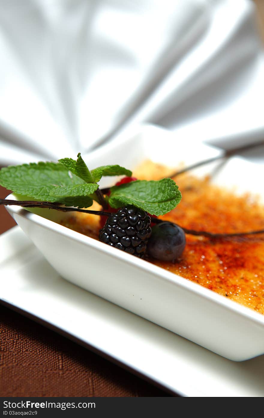 Dessert creme brulee with fresh mint and berries