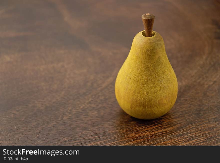 A wooden pear on dark wooden surface