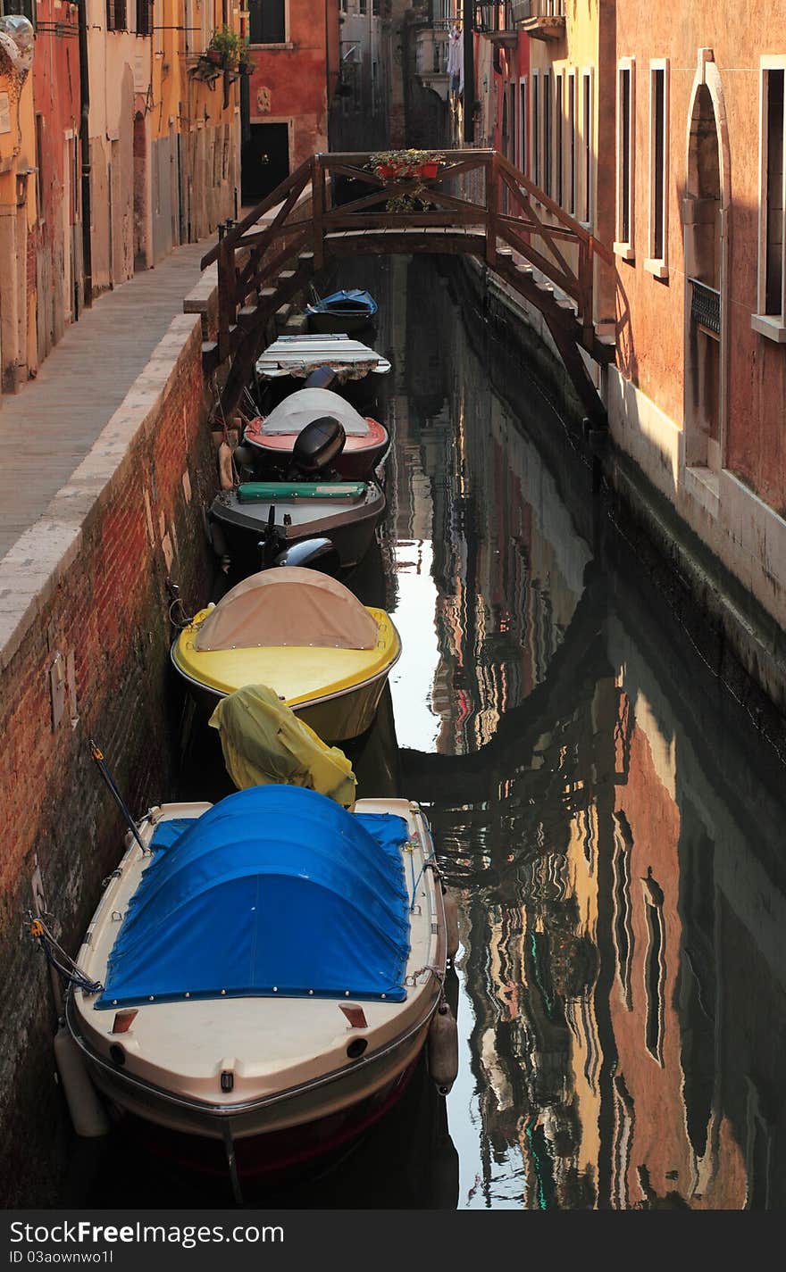 Engine powered boats parked near the walls on a narrow Venetian canal.