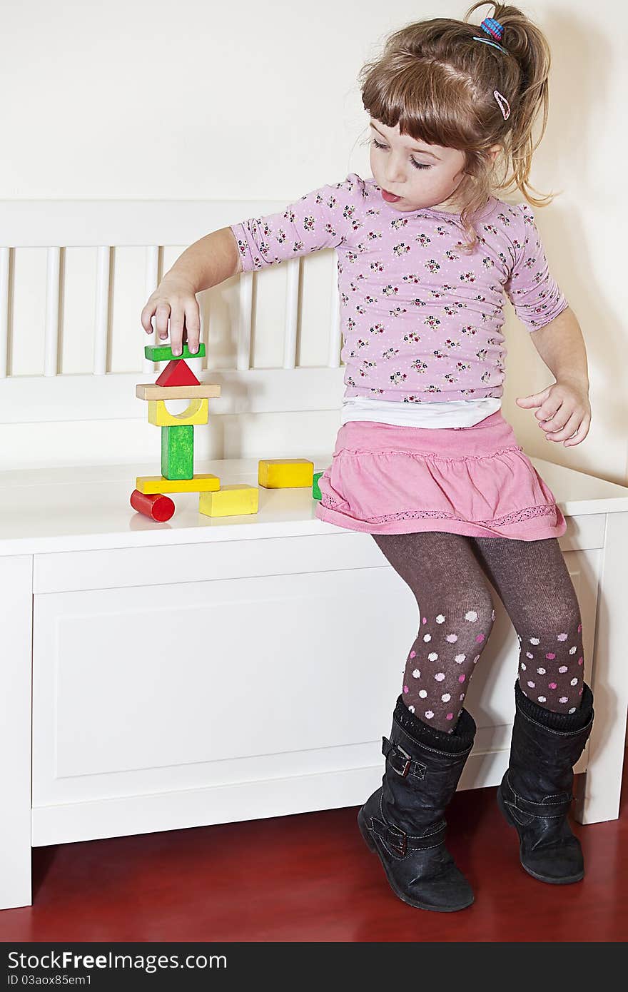 Little girl balancing colorful wooden blocks. Little girl balancing colorful wooden blocks