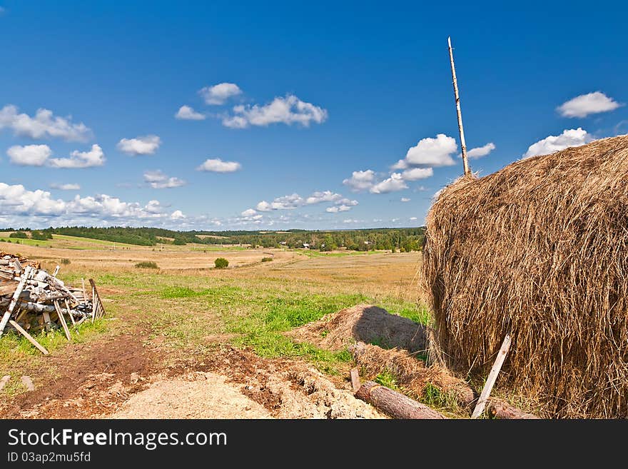 Blue sky and clouds over green hills with haystack