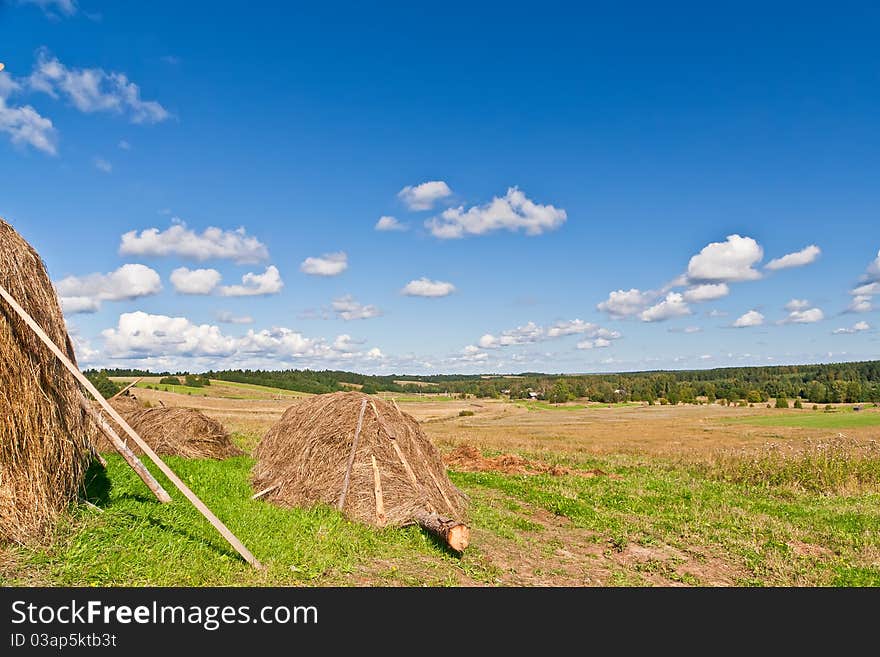 Blue sky and clouds over green hills with haystack