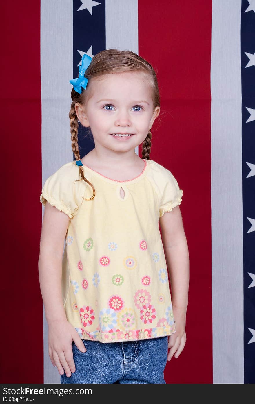 A happy American Girl standing in front of a red, white and blue background with stars.