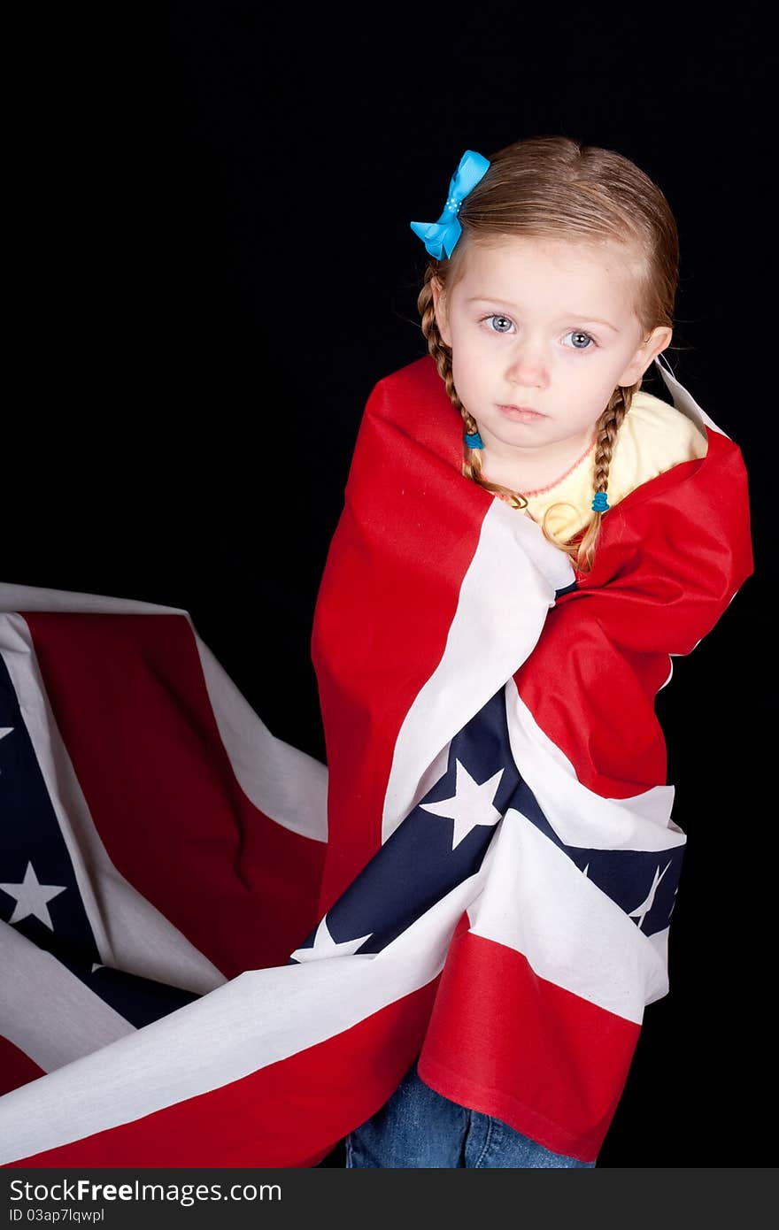 Girl with a confused look on her face. She is drapped in a patriotic design. There is a black background. Girl with a confused look on her face. She is drapped in a patriotic design. There is a black background.