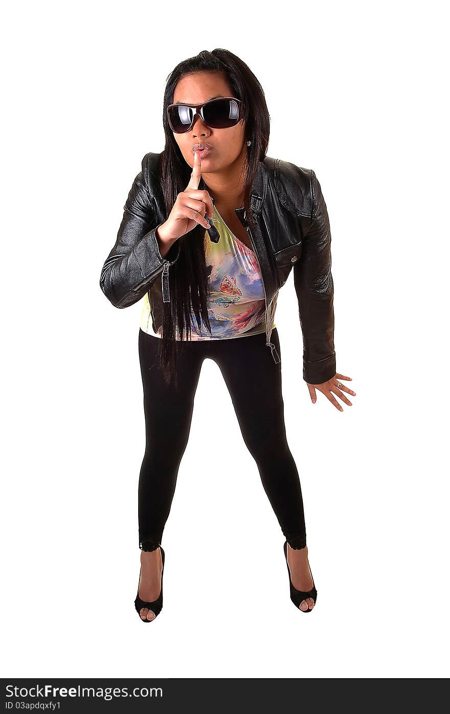 An Asian woman in a black leather jacket and tights, with sunglasses holds her finger for her mouth, be quiet, for white background. An Asian woman in a black leather jacket and tights, with sunglasses holds her finger for her mouth, be quiet, for white background.