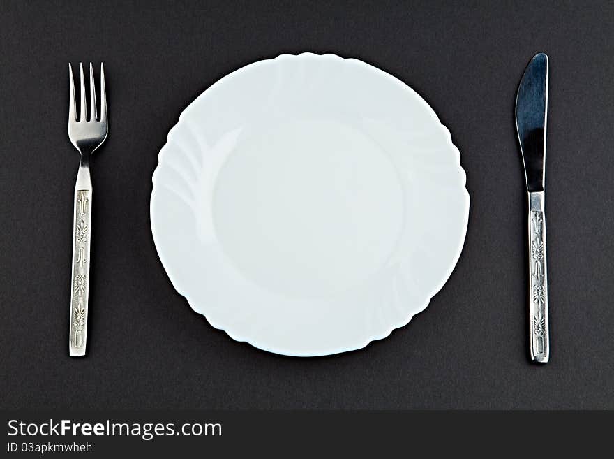 Plate a plug and a knife against a dark background. Plate a plug and a knife against a dark background