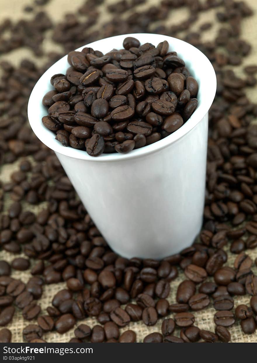 Coffee beans around a hessian bag isolated on white