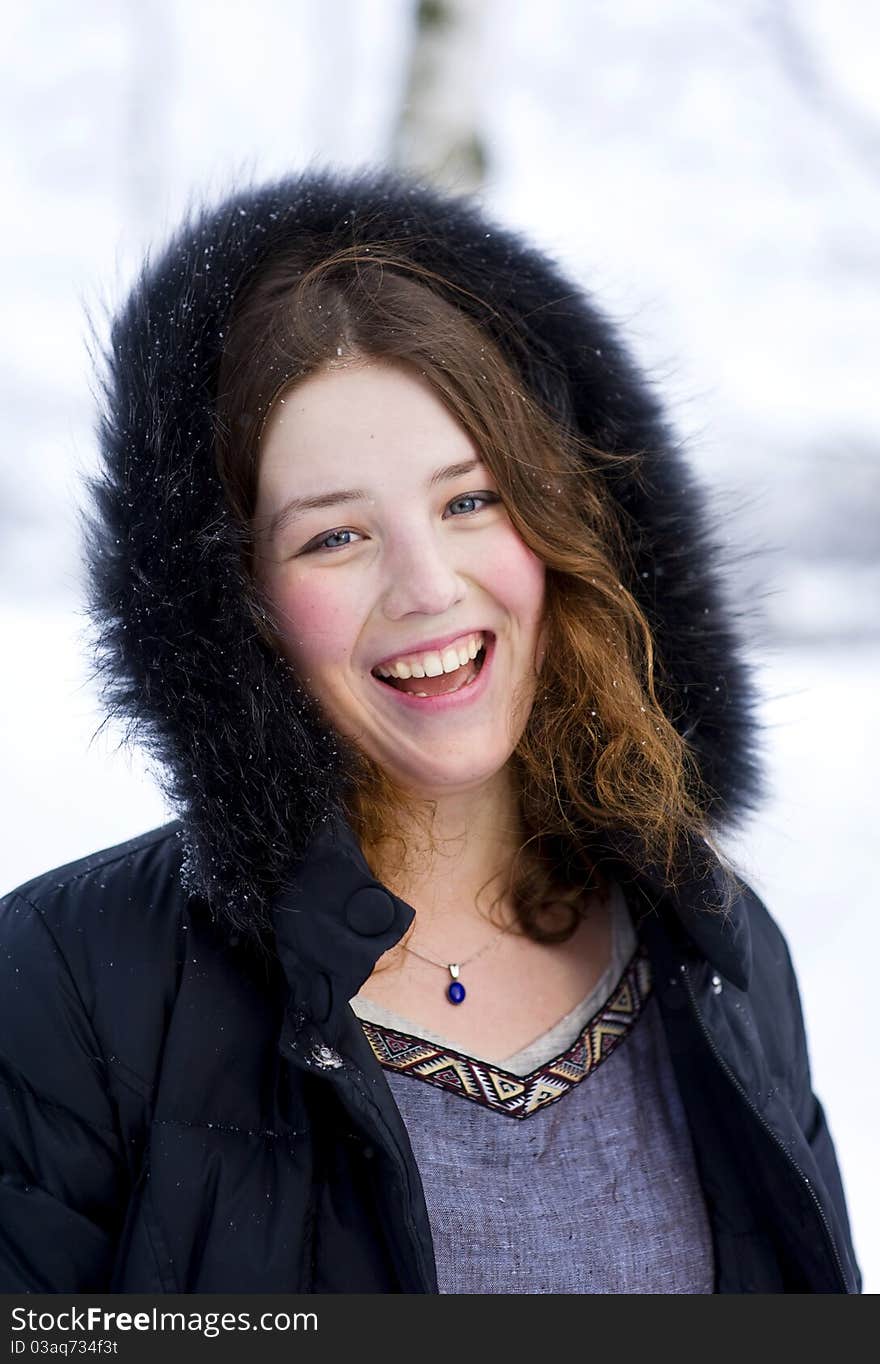 Laughing girl in the hood with fur in winter time