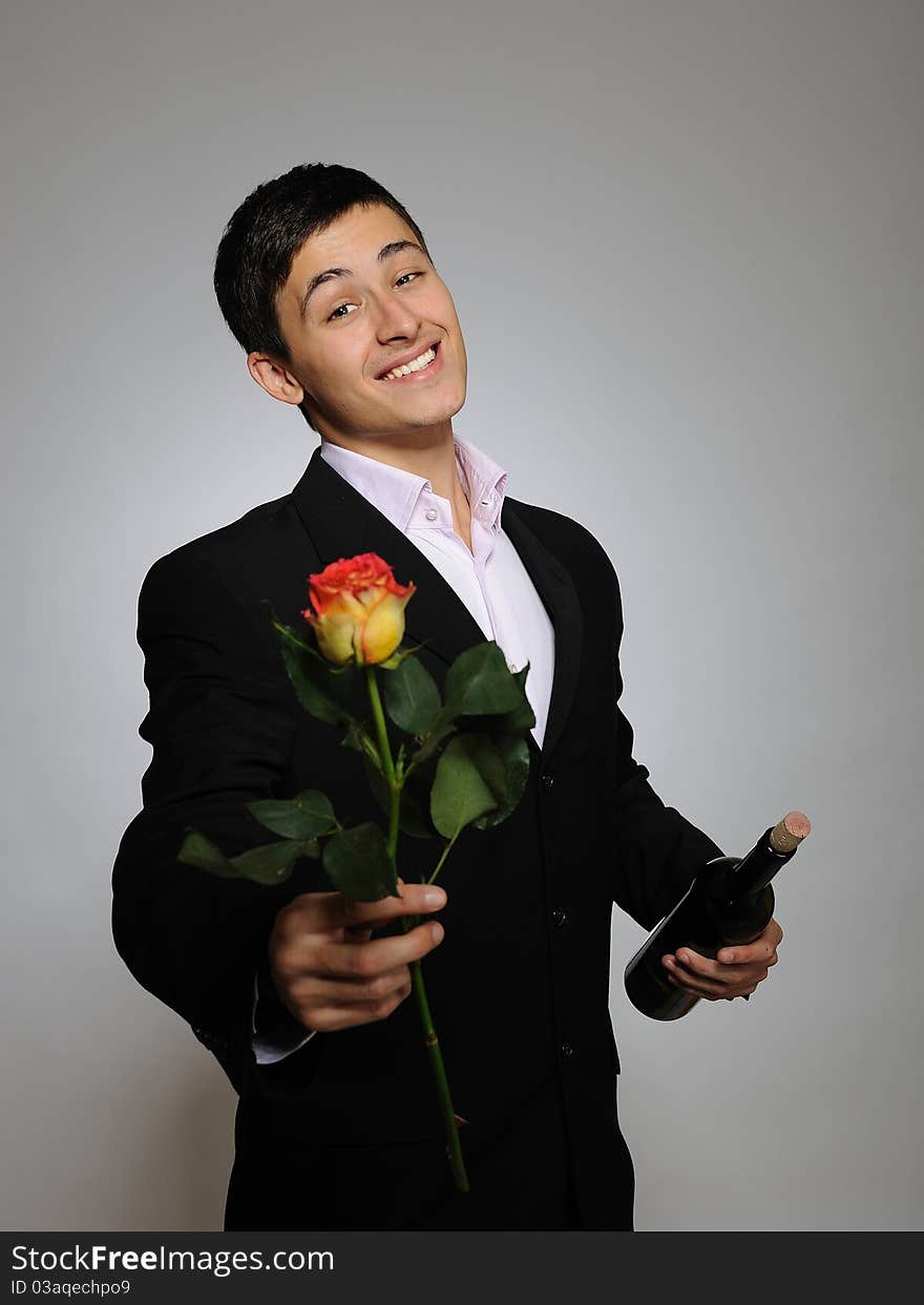 Handsome man holding rose flower and vine bottle